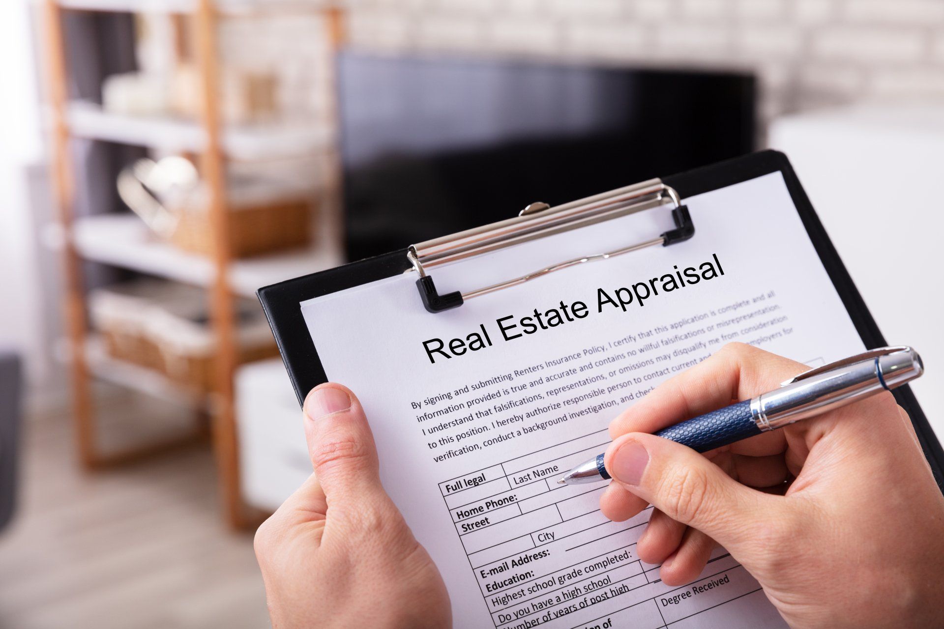 Close-up Of A Man's Hand Filling Real Estate Appraisal Form At Home